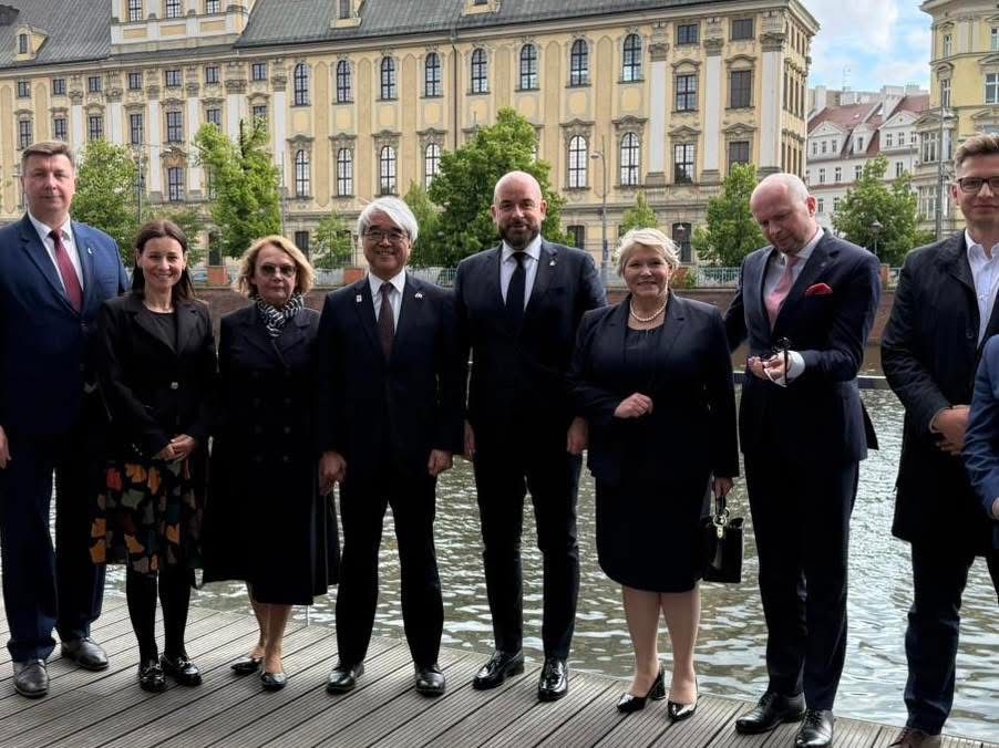 Uczestnicy oficjalnego spotkania pozują na tle Odry i zabytkowego budynku Uniwersytetu Wrocławskiego. Wśród nich: Ambasador Japonii Akira Kono, Drugi Sekretarz Fumiyasu Maruyama, Konsul Ukrainy Yurii Tokar, Dolnośląska Kurator Oświaty Ewa Skrzywanek oraz Prezydent Wrocławia Jacek Sutryk. Wydarzenie miało charakter symbolicznego przekazania sprzętu edukacyjnego.